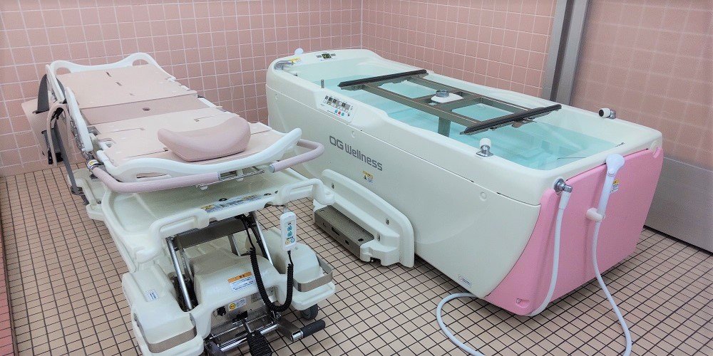 介護施設の浴室。機械浴（寝たまま入浴できる浴槽）と移乗用リフト装置が設置されている。
