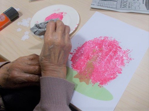 入居者による創作活動。ピンク色の絵の具を使った芸術制作の風景。